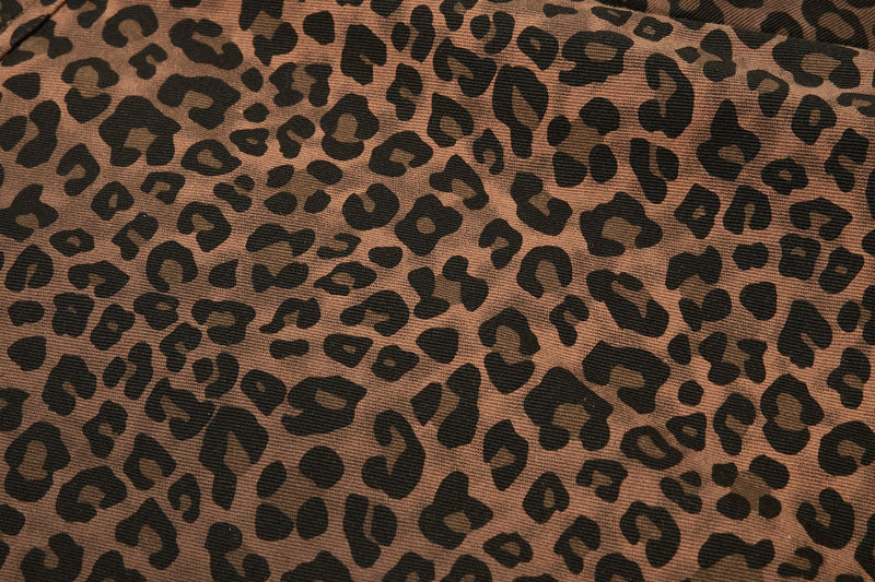 Close-up of brown leopard print shirt fabric with bold black spots and textured knit weave