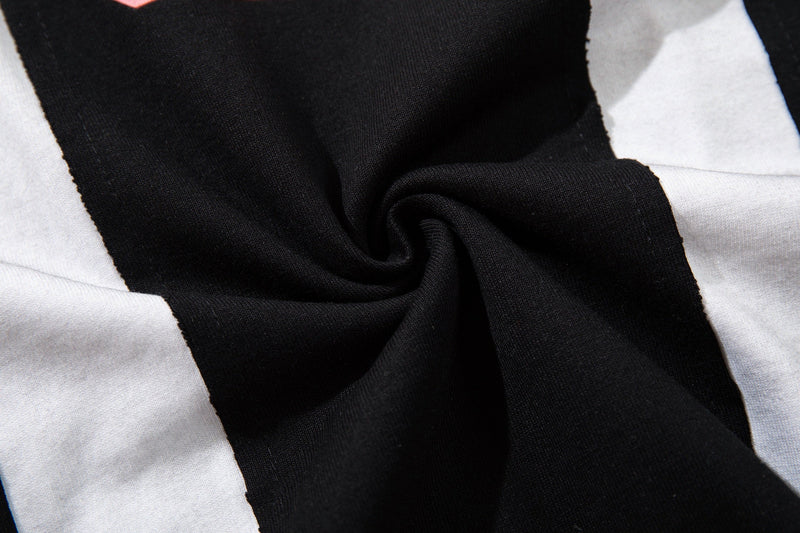 Close-up of black and white striped jersey fabric with a twisted center detail, showing a sporty streetwear tee texture