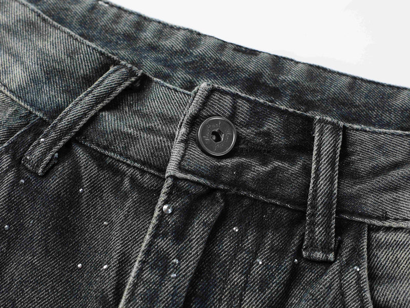 Close-up of waistband button and belt loops on black denim pants with rhinestone details