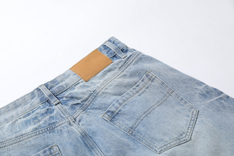 Light wash denim shorts back waistband close-up with tan label and pocket