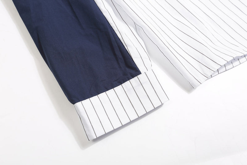 Close-up of navy sleeve and cuff with white pinstripe shirt hem