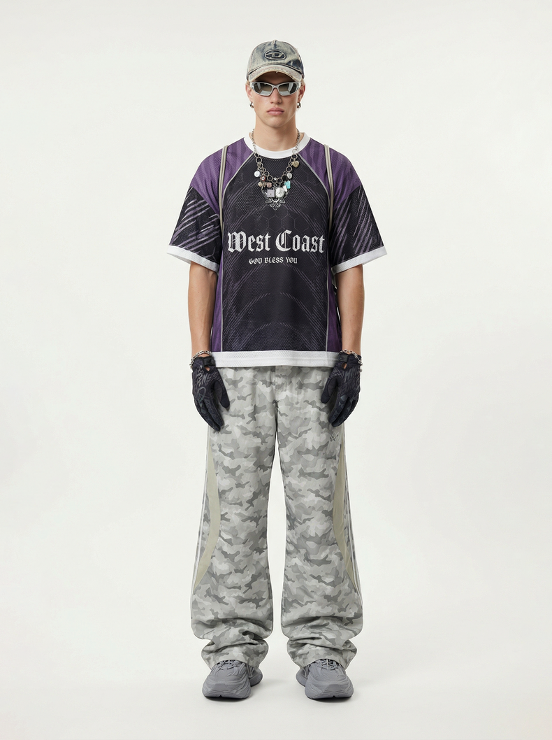 Model wearing a purple and black mesh soccer jersey with West Coast graphic, camo pants, gloves, and cap
