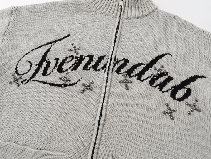 Close-up of light gray cardigan front showing script lettering and studded bead details