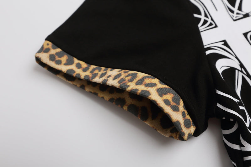 Black polo shirt sleeve with leopard print trim and bold white gothic cross graphic on the side