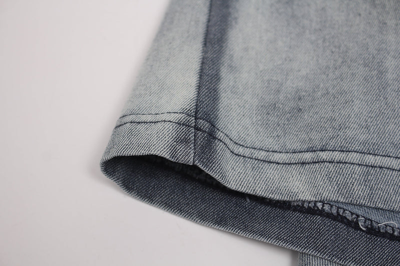 Close-up of a faded vintage-washed T-shirt hem with distressed stitching and denim-blue fabric texture