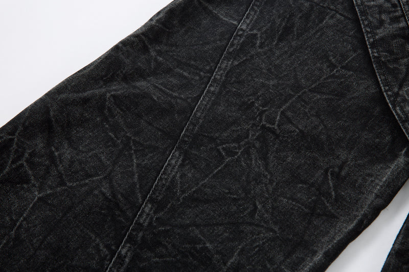 Close-up of black denim leg with crinkled wash and stitched panel seam