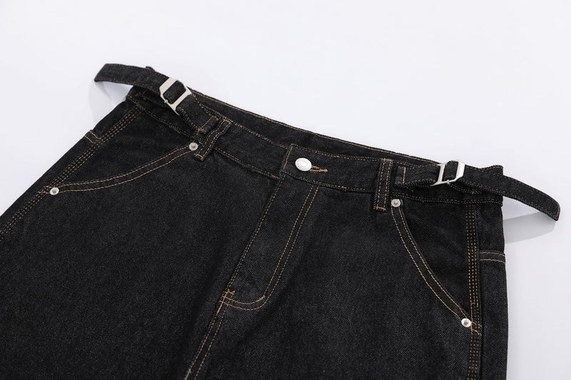 Close-up of black denim shorts waistband with belt loops, button, and side buckle straps