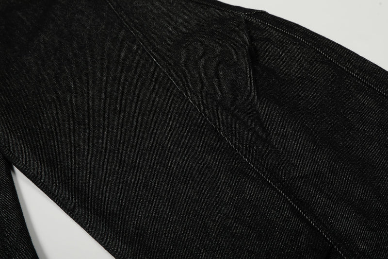 Close-up of black denim leg panel with diagonal seam and smooth wide-leg fabric