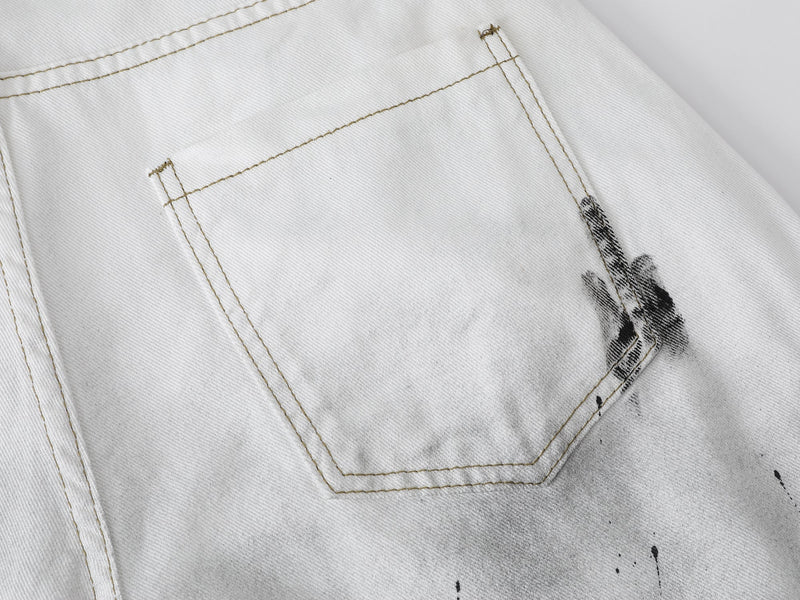 Close-up of the back pocket on white denim shorts with black paint splatter