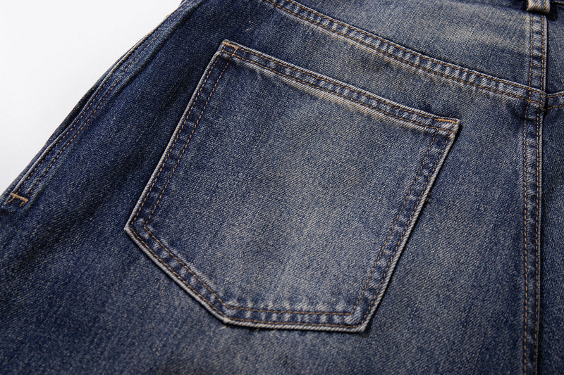 Close-up of back pocket and faded mid-blue denim texture with contrast stitching