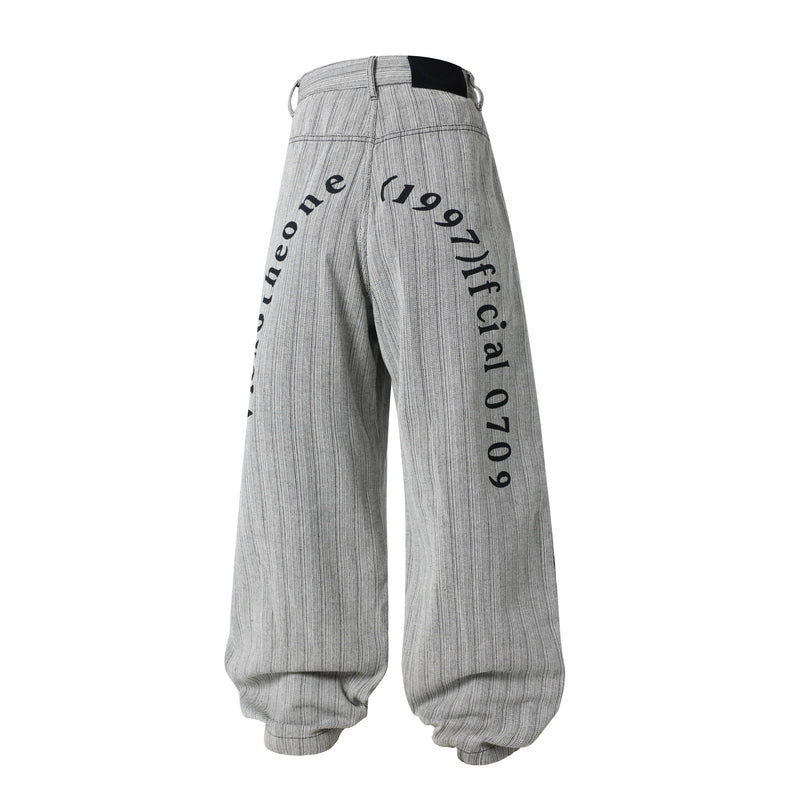 Back view of gray wide-leg balloon pants with printed lettering down the legs and waistband detail