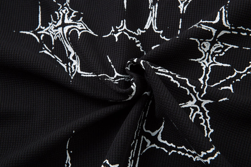Close-up of black polo shirt fabric with white gothic thorn cross graphics and textured dark streetwear style