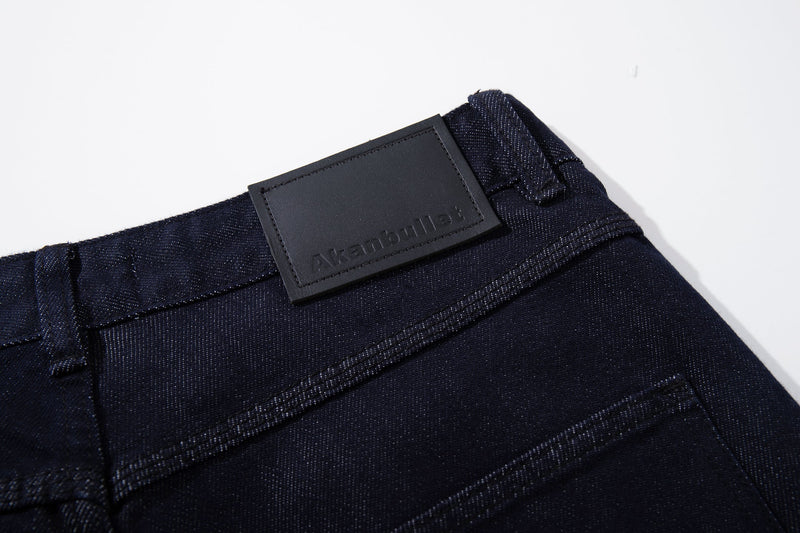 Close-up of black logo patch on the back waistband of dark wash jeans