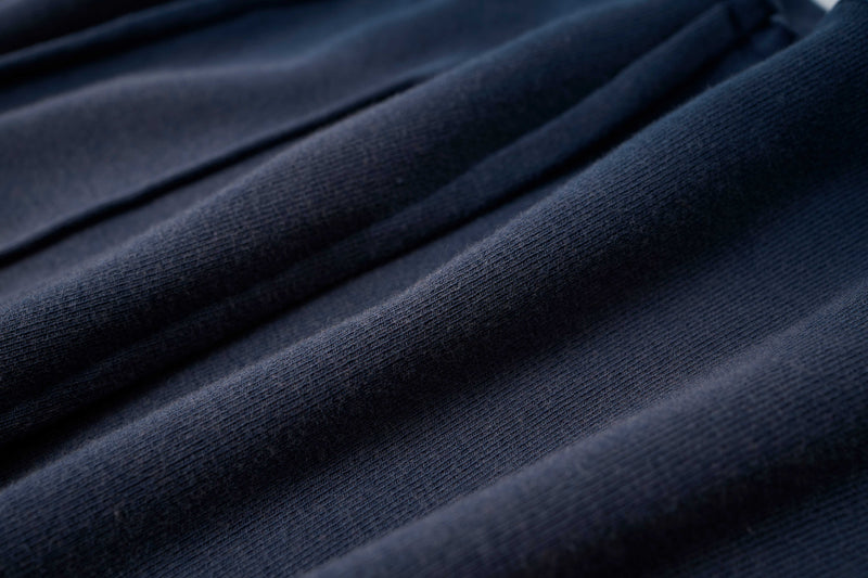 Close-up of navy cotton tee fabric with sculpted panel seams and textured raw-edge streetwear detailing