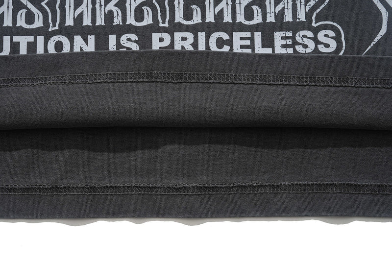 Folded vintage washed black graphic T-shirt with distressed white typography and exposed seam details