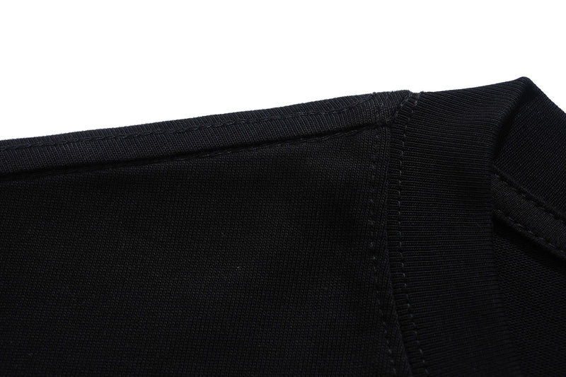 Close-up of a black graphic tee neckline with ribbed collar and stitched shoulder seam on a white background
