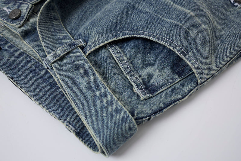 Close-up of light wash denim shorts pocket opening and strap at the side seam