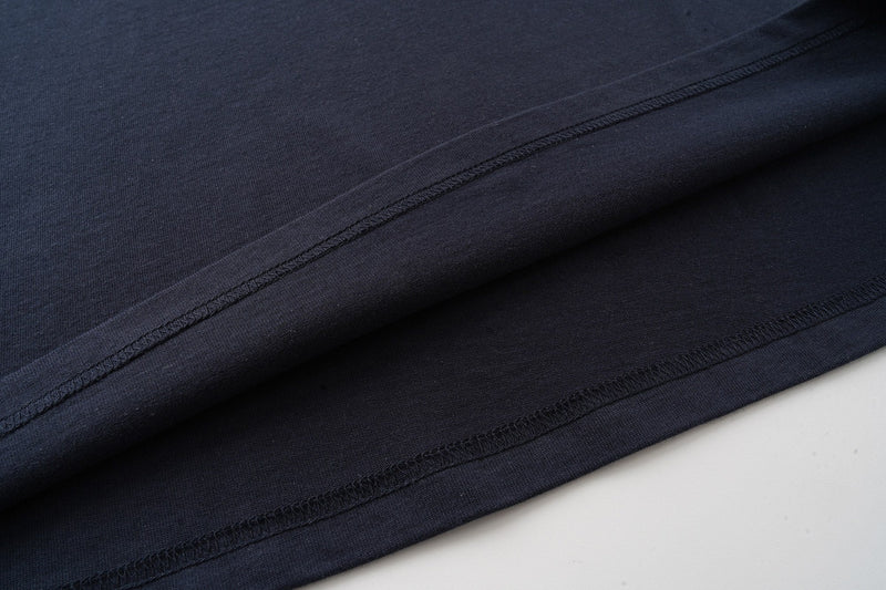 Close-up of dark navy graphic T-shirt hem with visible stitched seams and soft cotton texture