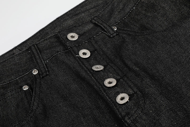 Close-up of black denim button fly and waistband stitching on the front panel