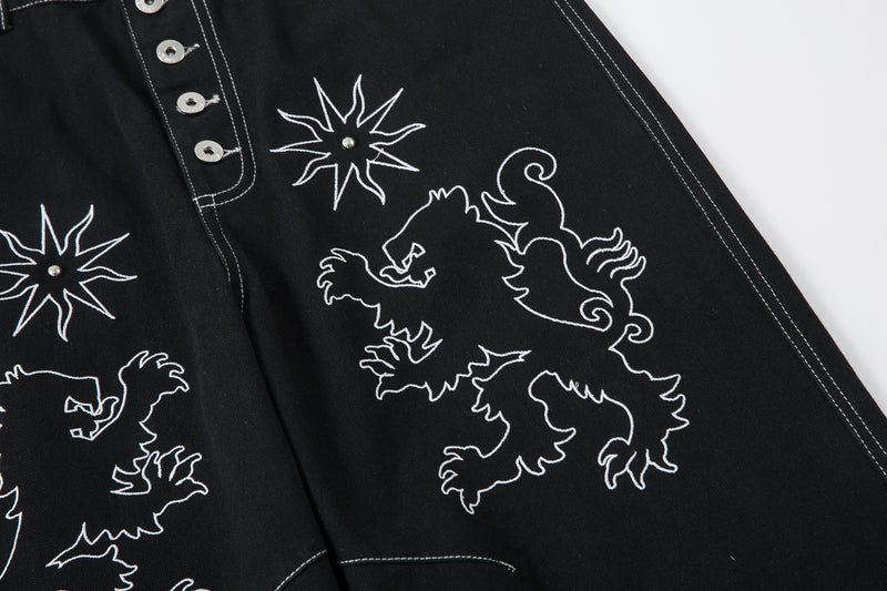 Close-up of black jeans front with lion embroidery and star design