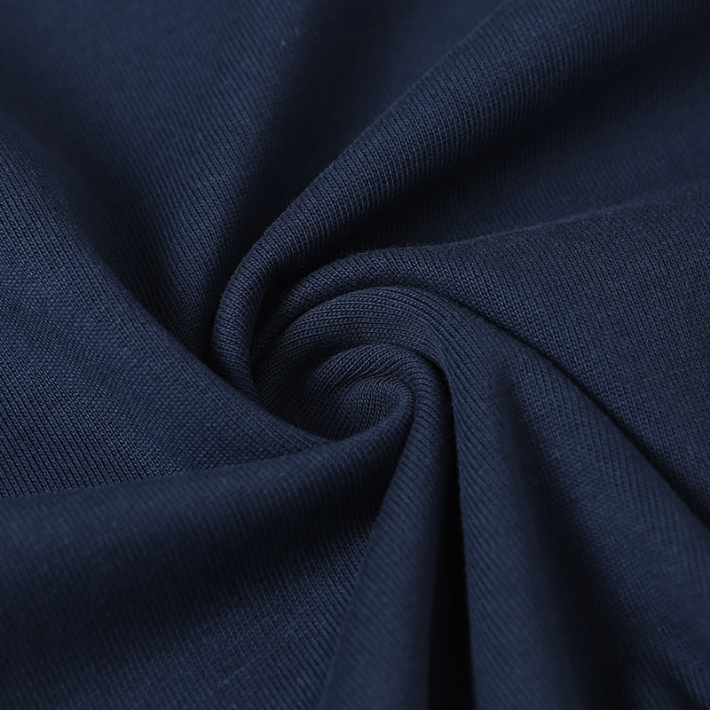 Close-up of navy cotton fabric with a soft spiral fold and smooth ribbed texture, ideal for an athletic streetwear tee