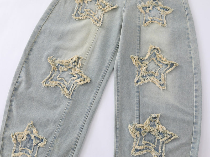Front legs close-up showing frayed star patches on light wash baggy jeans