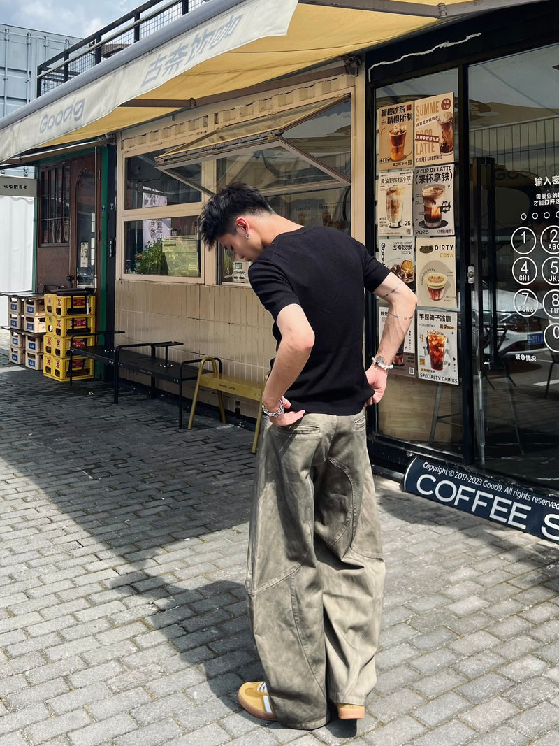 Back view of model wearing light-washed olive wide-leg jeans with curved seam panels