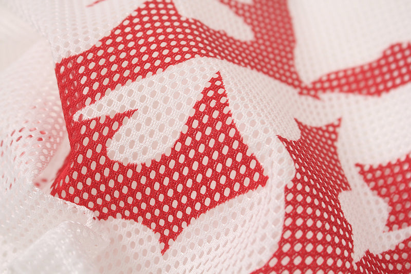 Close-up of white mesh jersey fabric with bold red flame-like sigil pattern and breathable athletic texture