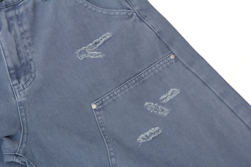 Close-up of blue denim with ripped distressing and utility pocket detail