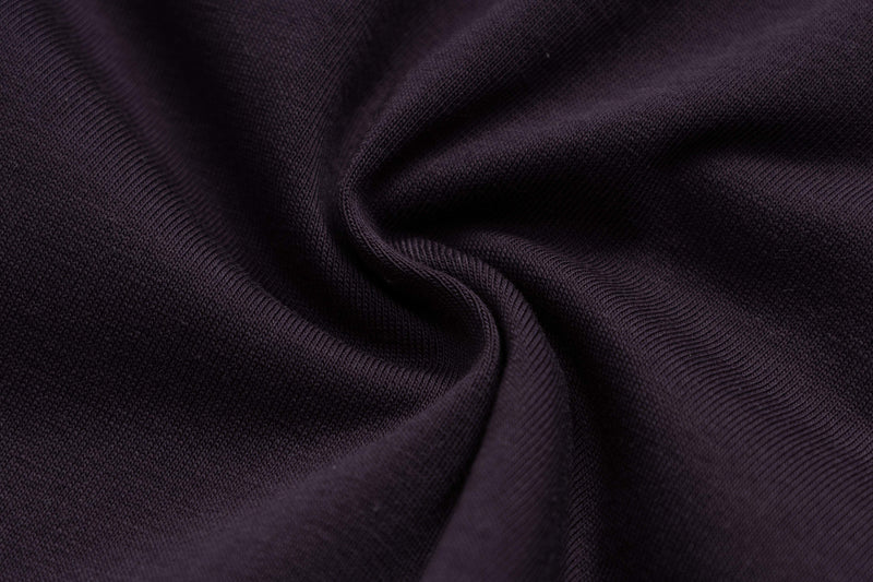 Close-up of dark purple ribbed fabric with soft folds, showing the texture of an oversized Y2K graphic tee