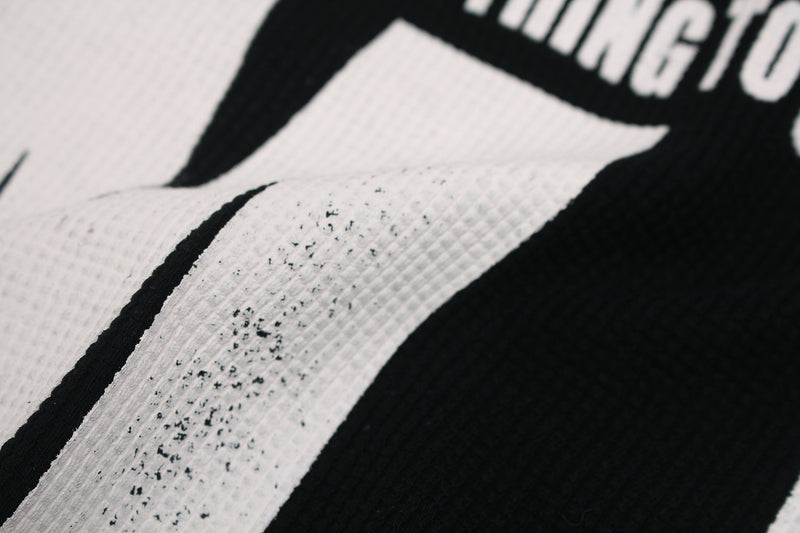 Close-up of black graphic T-shirt print with bold white newspaper-style lettering and distressed texture