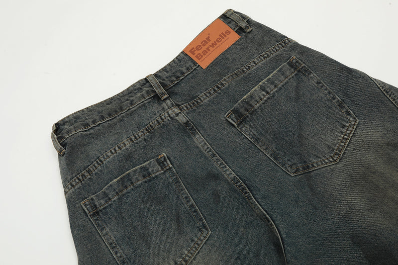Close-up of back waistband and pockets on dark wash jeans with brown label patch