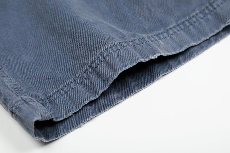 Close-up of washed blue pant hem with stitched cuff and frayed edge