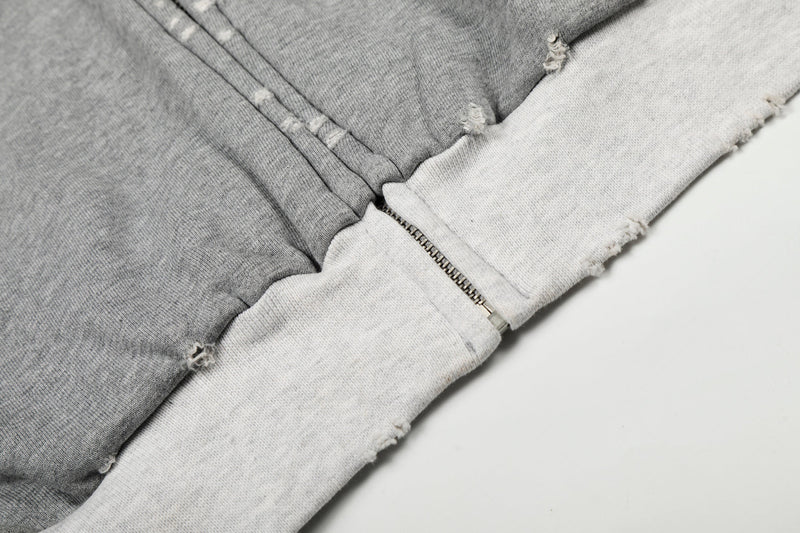 Close-up of lower hem and front zipper on gray and white distressed zip-up hoodie