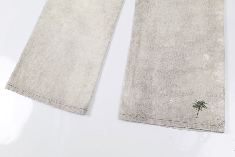 Close-up of both leg hems on washed botanical print wide-leg jeans