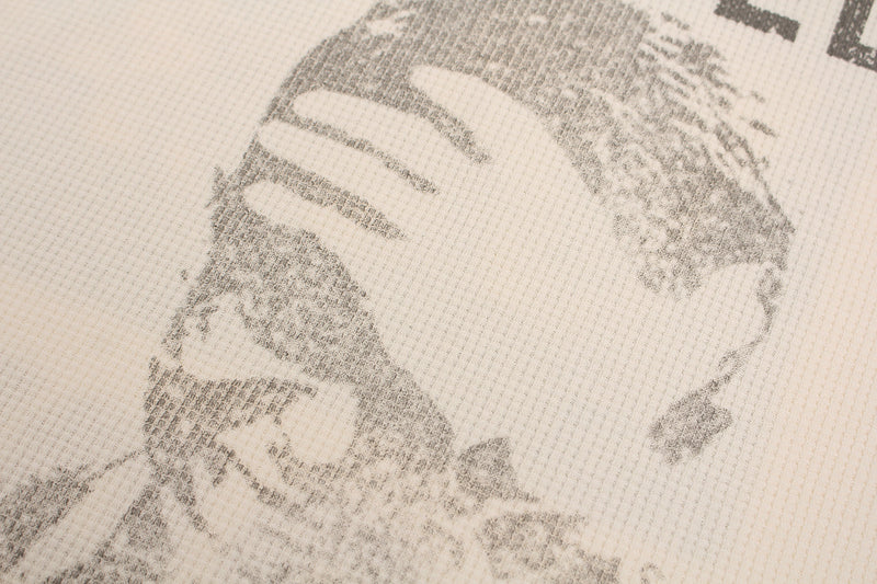 Close-up of a cream waffle knit tee with faded black streetwear graphic print and textured fabric detail