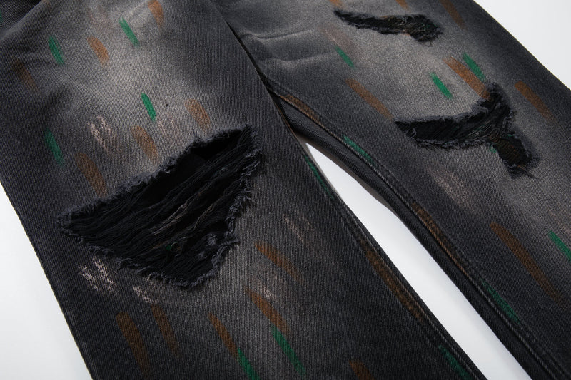 Close-up of distressed thigh and knee rips on washed black painted jeans