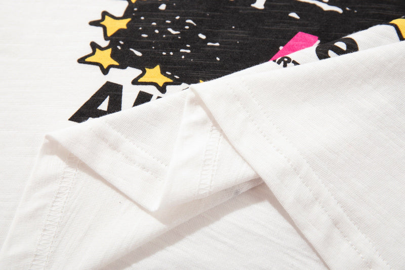 Close-up of a white ringer T-shirt with a bold black cat graphic, yellow stars, and pink accent details