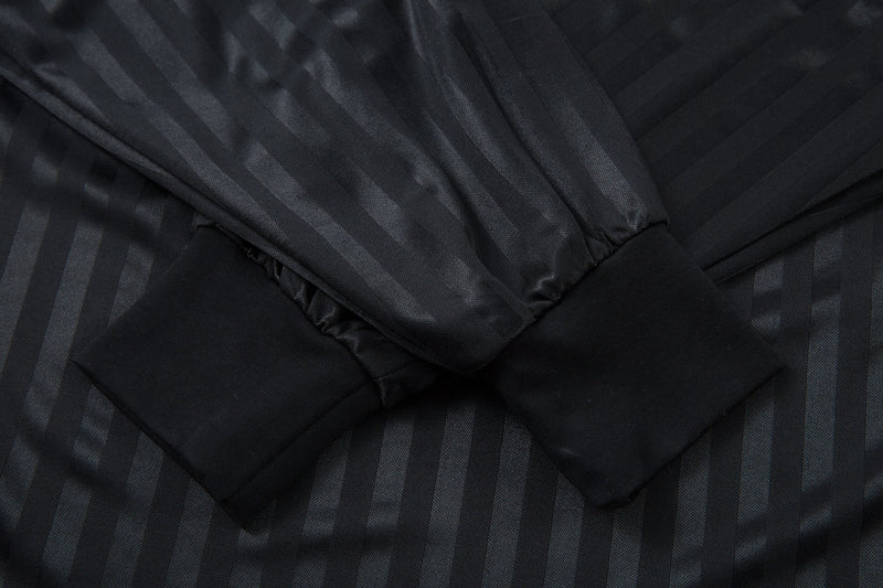 Close-up of black jersey fabric showing subtle vertical stripe texture and folded sleeve