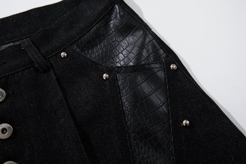 Close-up of back yoke and side seam on black denim pants with crocodile-textured panel detail
