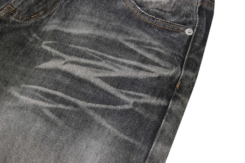 Close-up of faded black denim with whiskering and side seam stitching