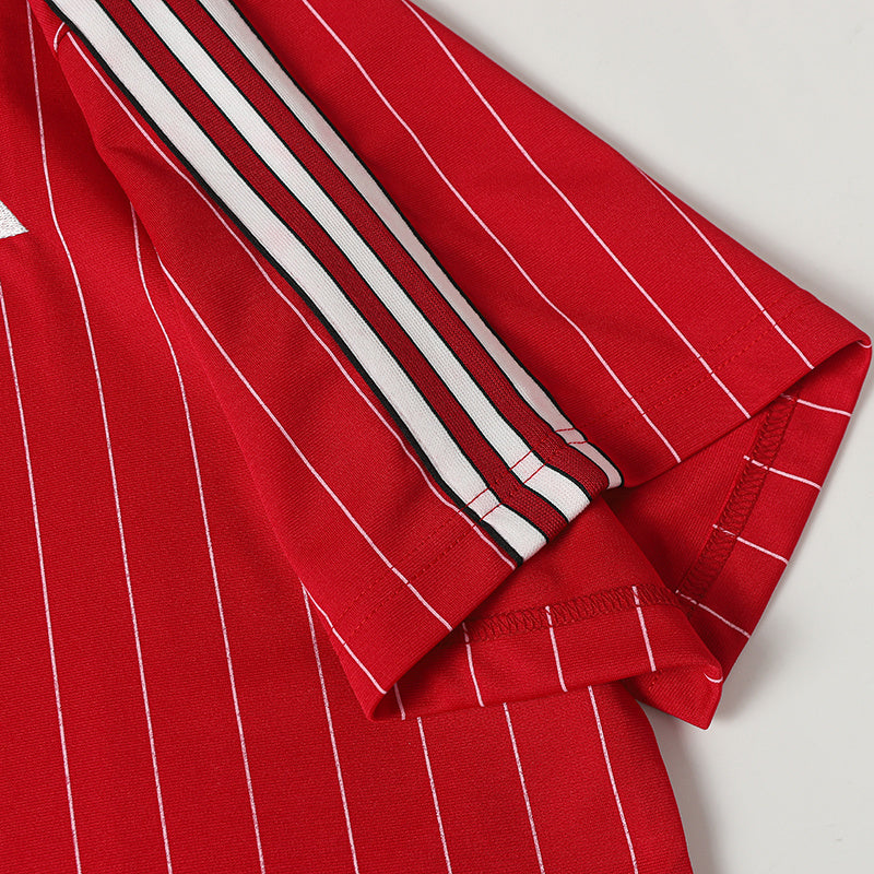 Red pinstripe soccer jersey sleeve with white and black side stripes on a textured performance tee