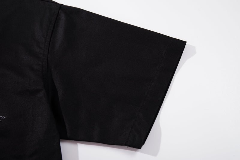 Black short sleeve button-up shirt sleeve on a white background, showcasing a sleek streetwear rock guitarist style
