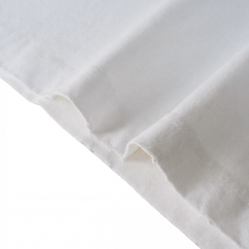 Close-up of a white cotton T-shirt sleeve with a raw hem and soft vintage-washed fabric texture