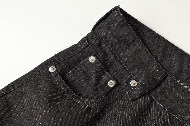 Close-up of back pocket stitching and silver rivets on black denim waistband
