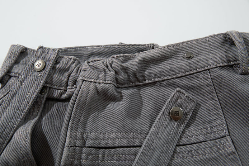 Close-up of gray jeans front waist with belt loops, button, and cargo pocket flap