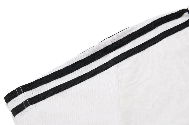 White polo shirt sleeve with black double stripe trim and contrast stitching, close-up detail of vintage streetwear style
