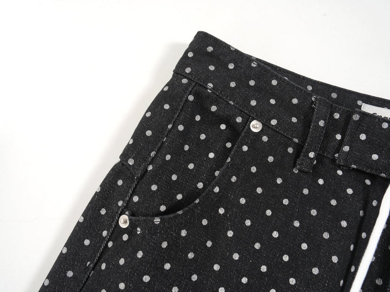 Side waist detail of black polka-dot denim pants with belt loop and pocket edge
