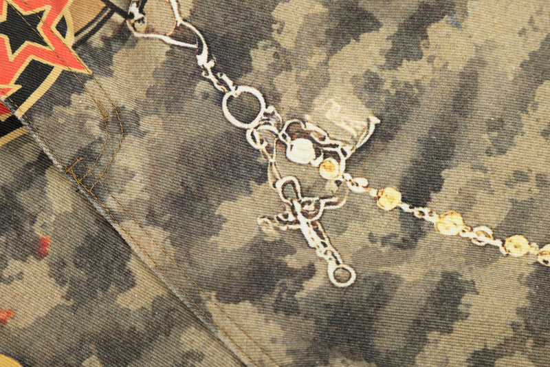 Close-up of chain detail on camo patchwork denim with stitched seam and star graphic edge