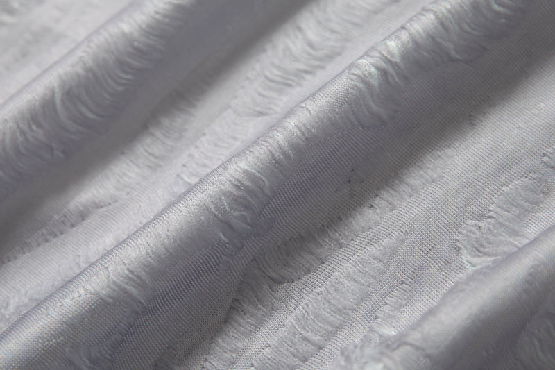 Close-up of white textured mesh fabric with distressed patchwork detailing and subtle sheen